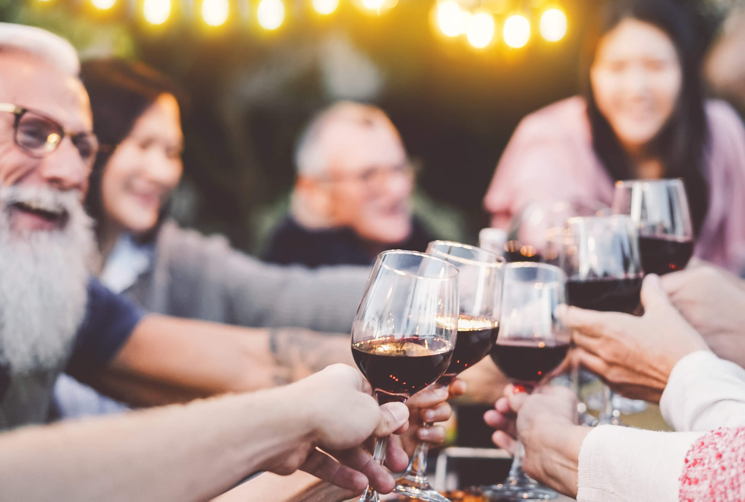 Sommerlicher Grillabend unter Freunden mit Wein und gemütlicher Lichterkette